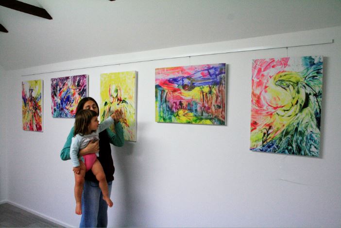 Woman and child lookign at paintings. Encaustic Art painting Exhibition, England, UK. Nov 2018.